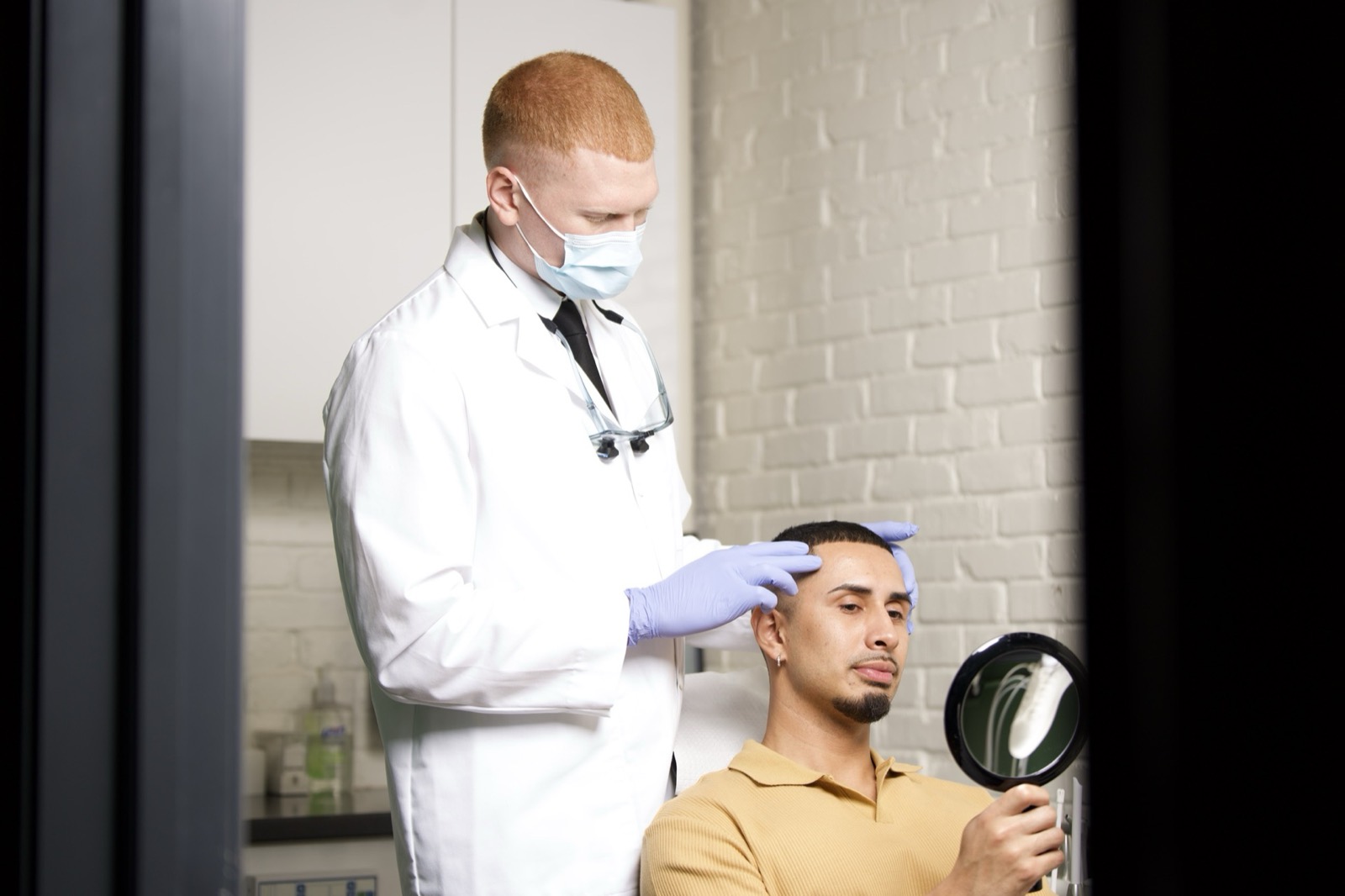 Dr. Colby with a patient holding a hand mirror, seen through the doorway