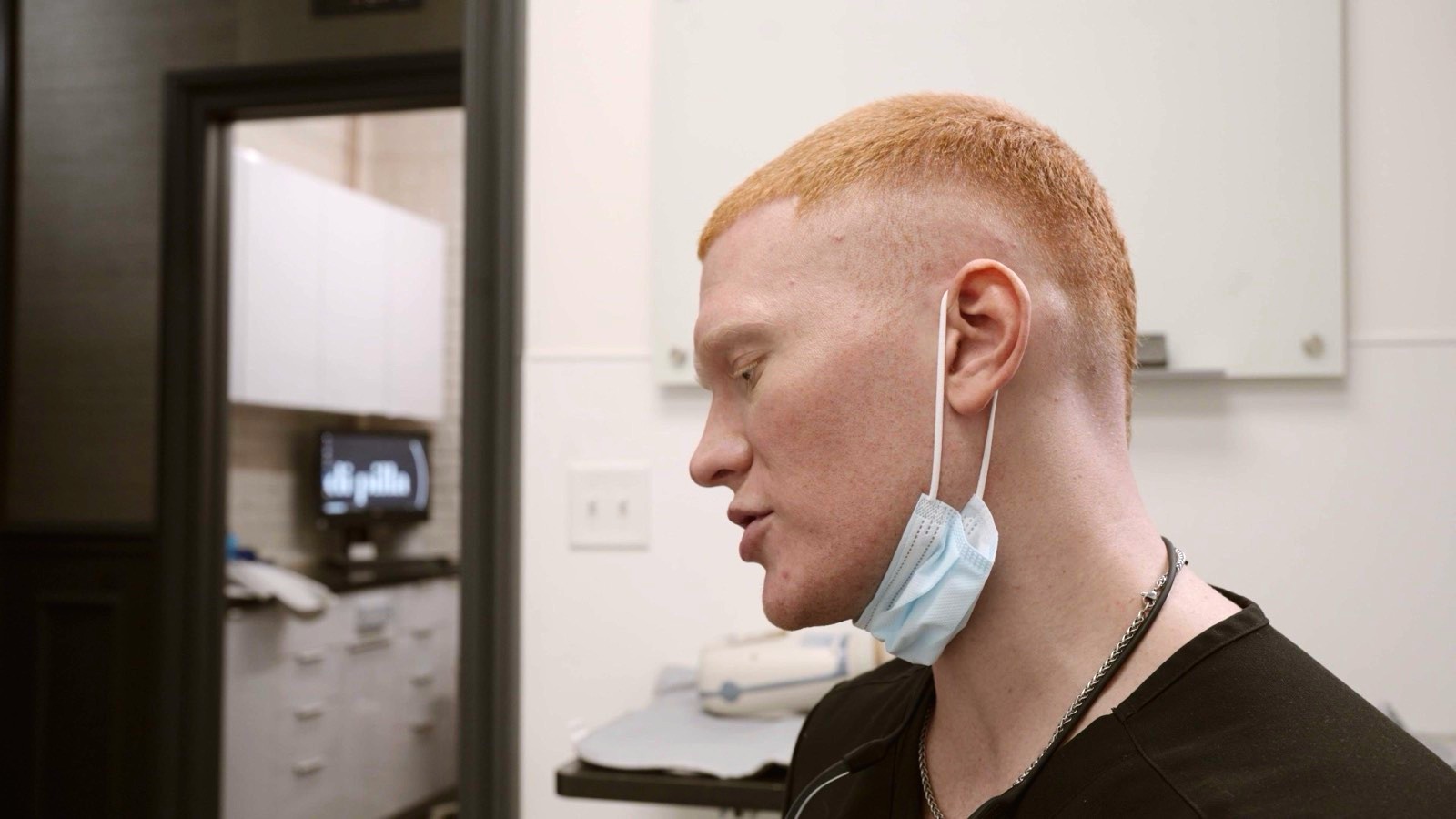 Dr. Colby, mask down, listening to a patient