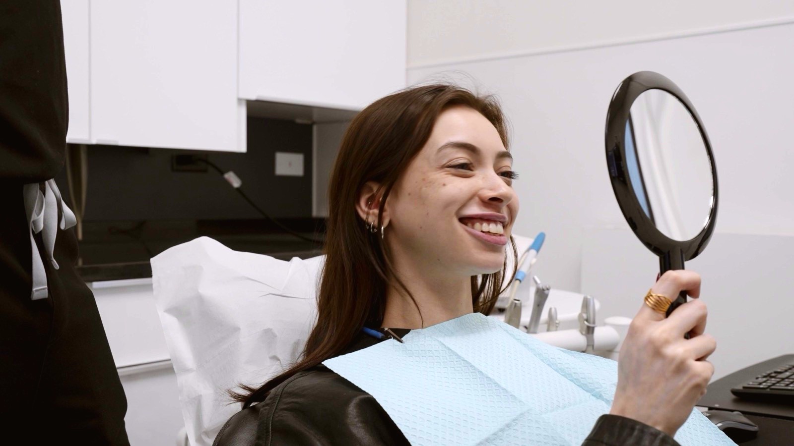A patient laughing as she checks her smile in a hand mirror
