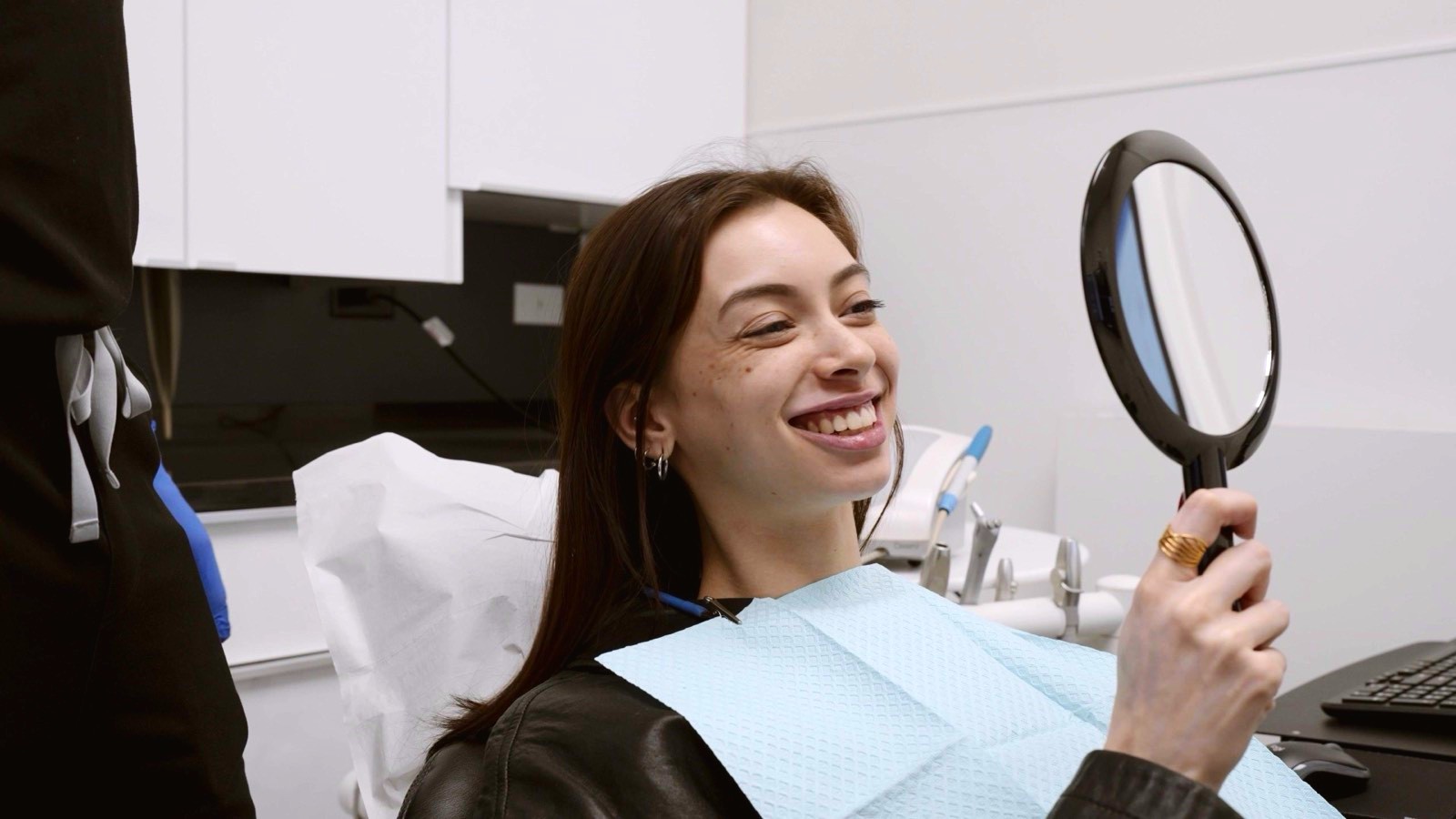 A patient checking her smile in a hand mirror