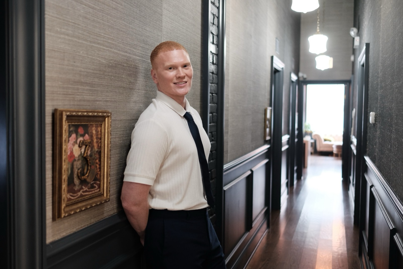 Dr. Colby in the hallway at Pearl, beside a gilt-framed painting