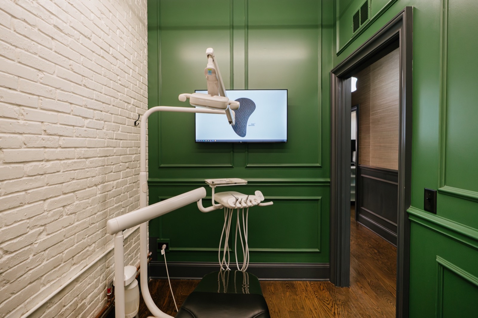 A treatment room at Pearl seen through the doorway, its walls painted deep green