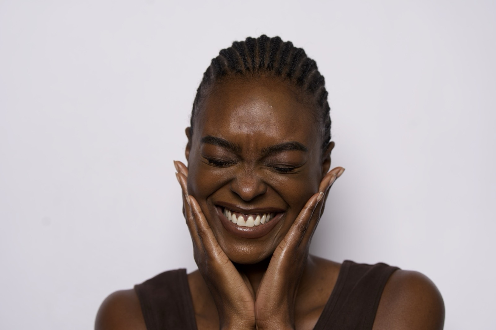 A woman laughing, her hands on her cheeks