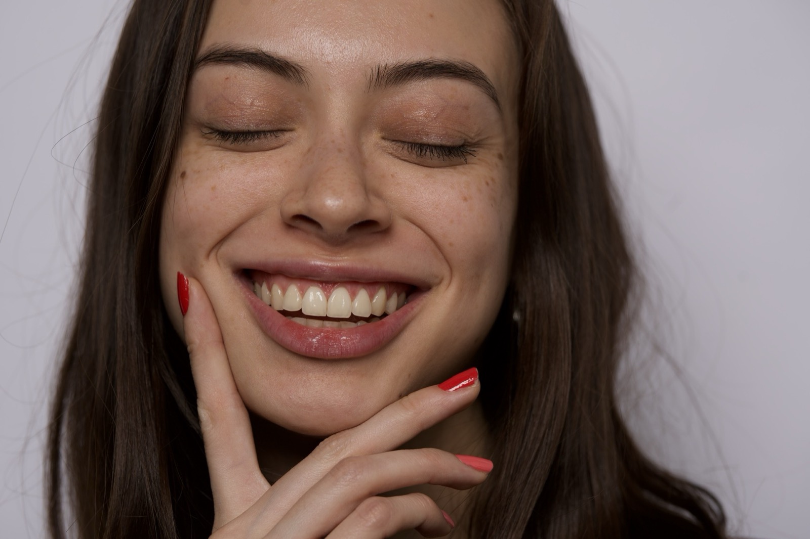 A woman laughing, eyes closed